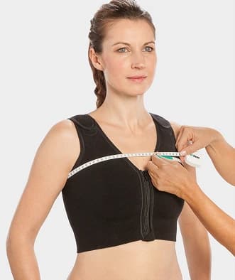 Female model standing while someone measures her bust size for a custom-made compression garment.